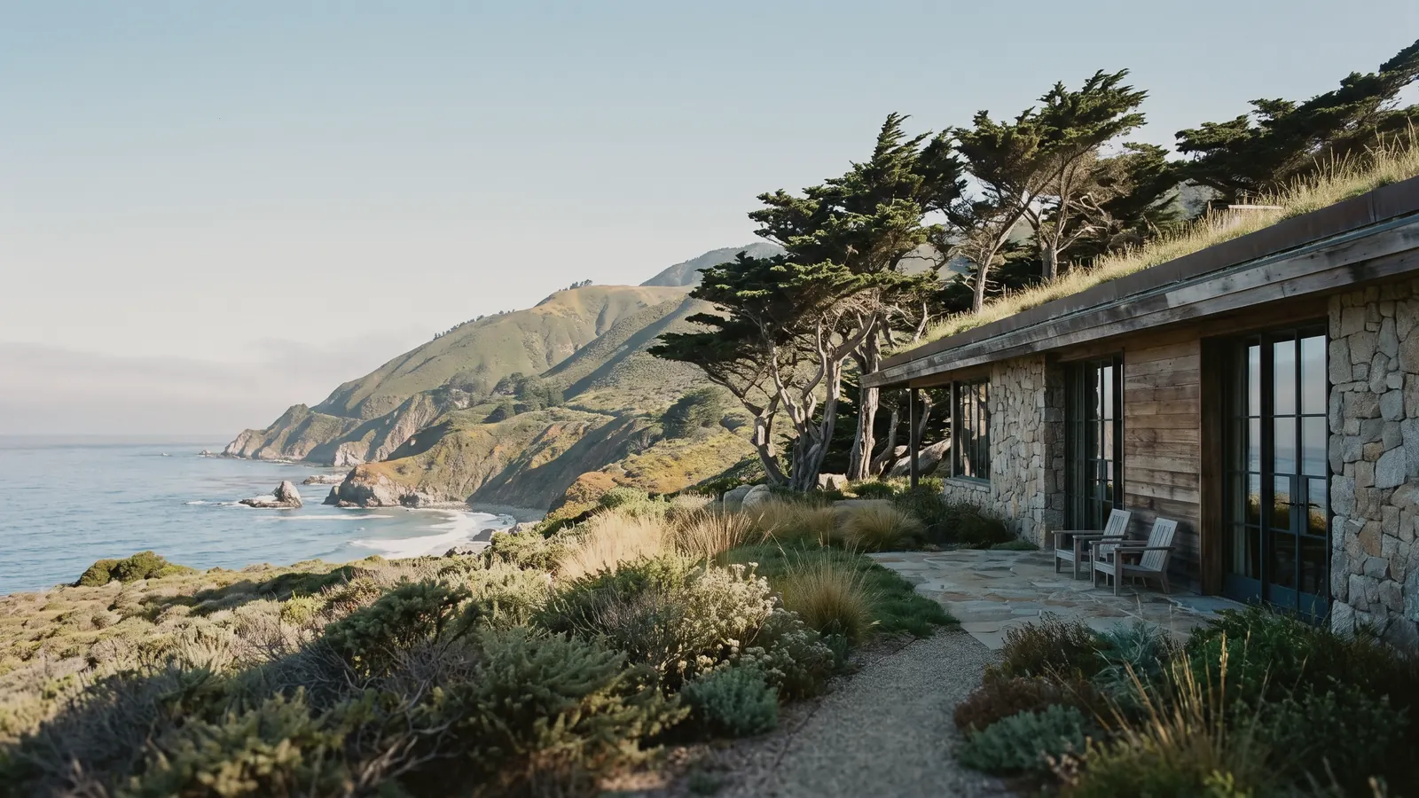 A stone and wood home on a grassy bluff above the ocean