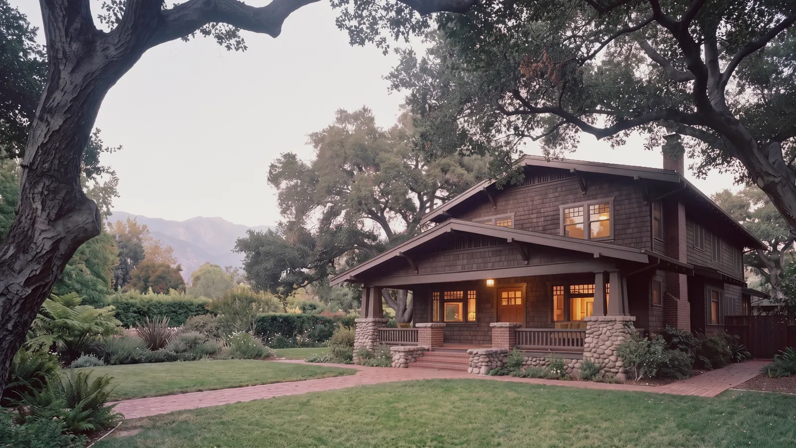 A craftsman home with a wide front porch under old oak trees